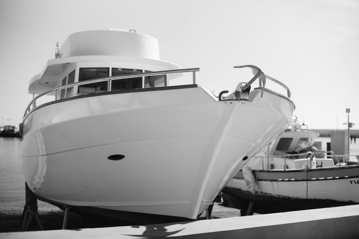 A white motor yacht with an anchor on the bow moored in a harbor