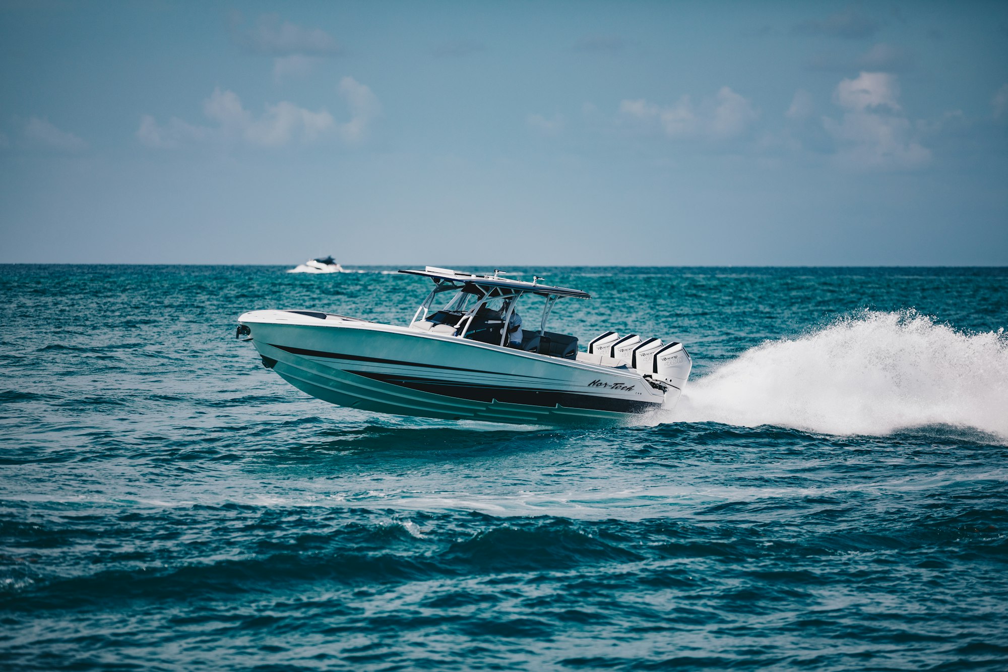 A center console offshore boat with quad outboards running through open saltwater