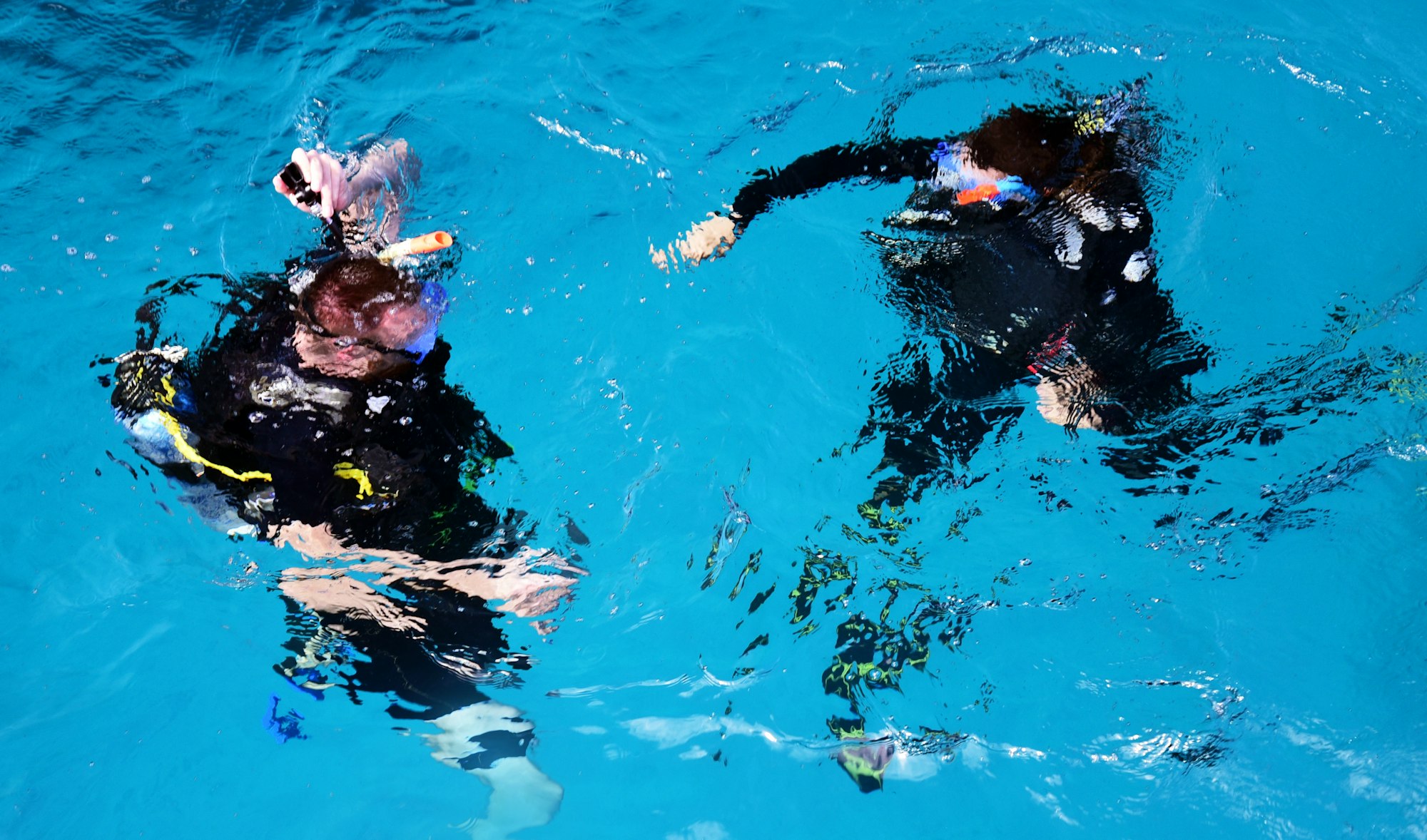 Divers submerging in blue water with an instructor
