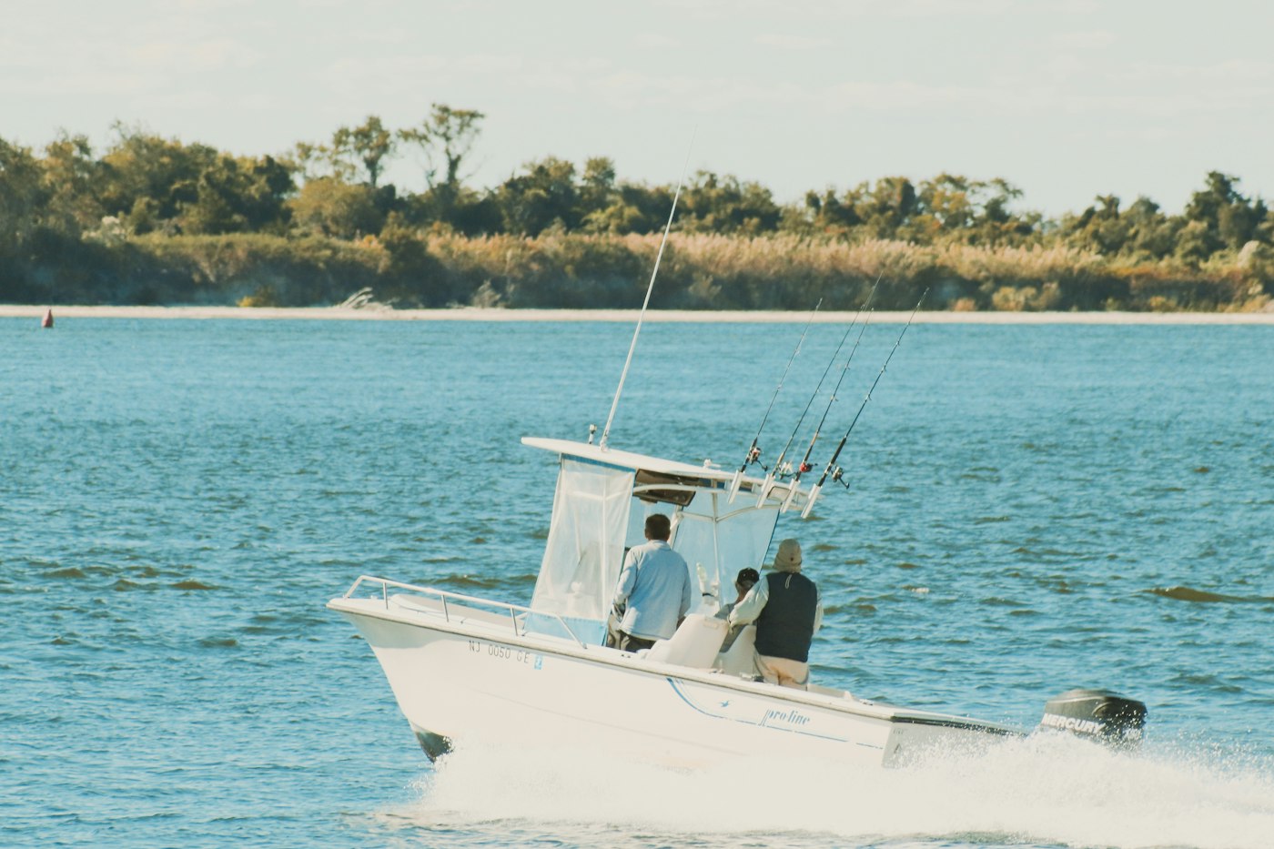 A white motorboat with fishing rods on a sunny day