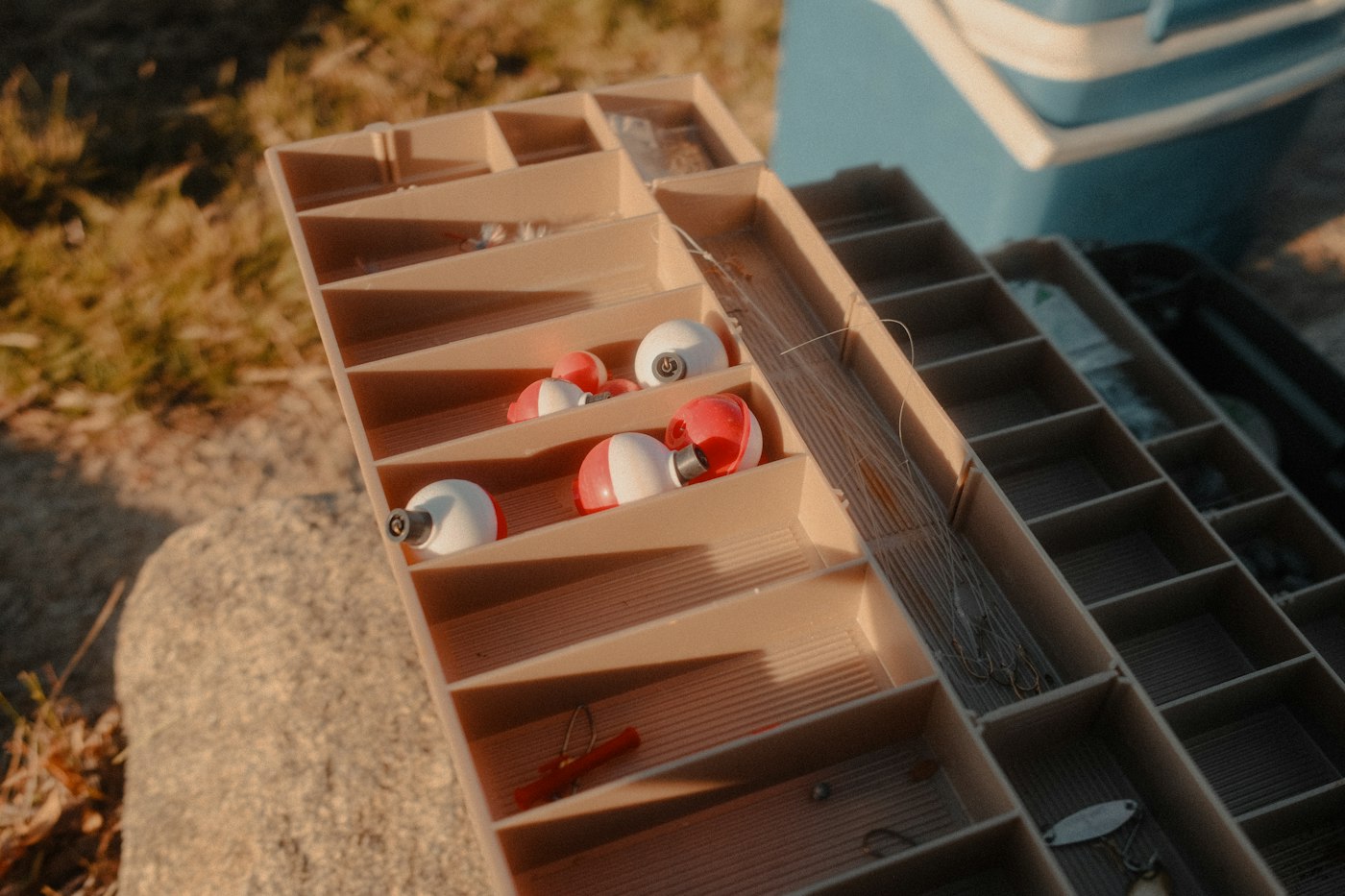 A fishing tackle box with red and white bobbers