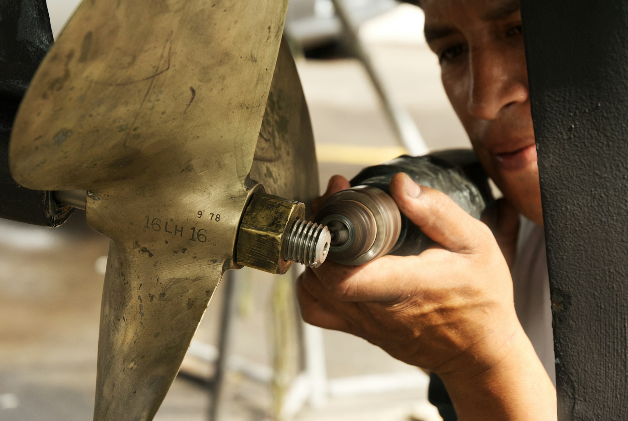 A worker drilling on a ship propeller shaft