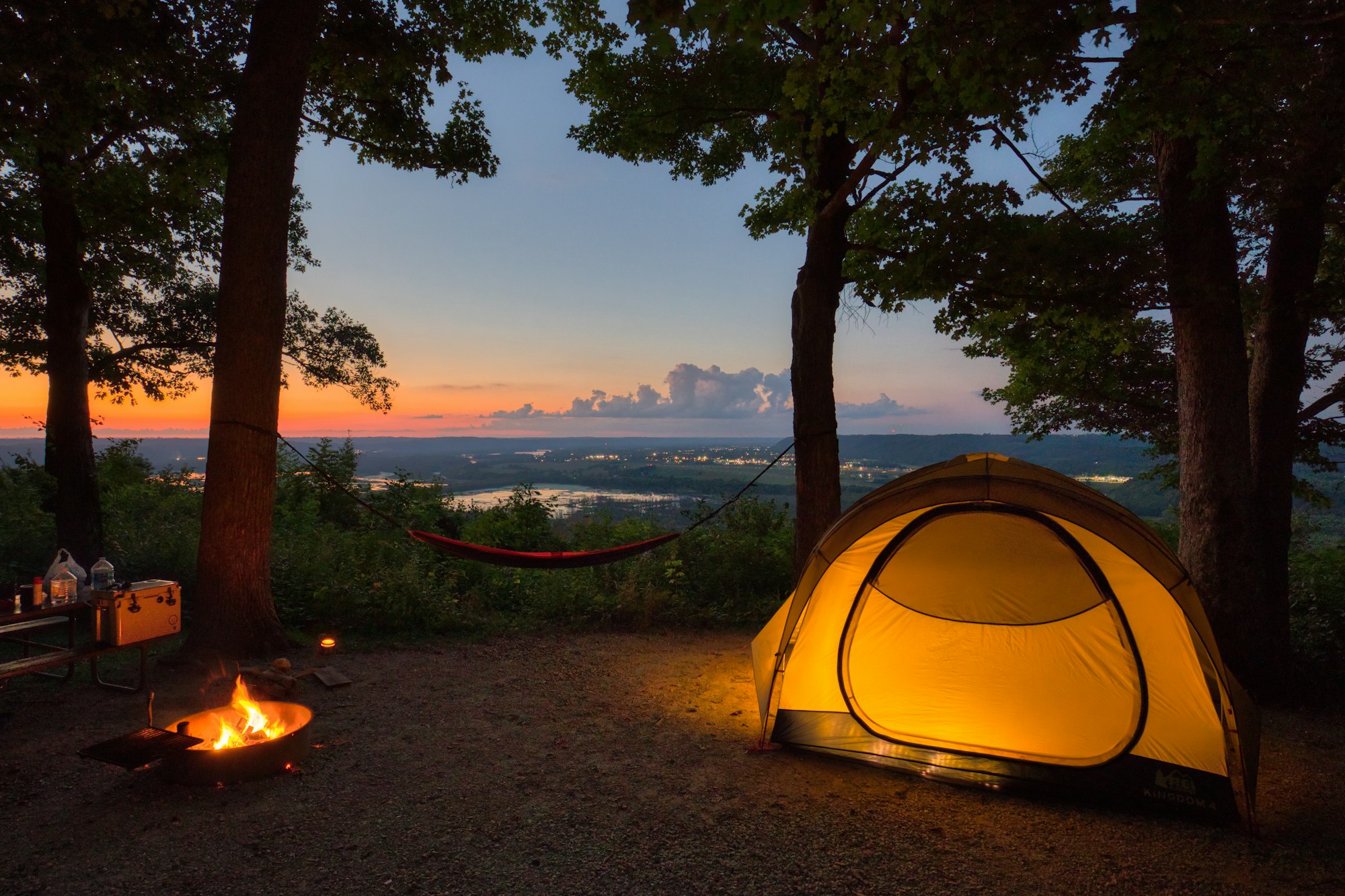 A tent set up in the woods at sunset