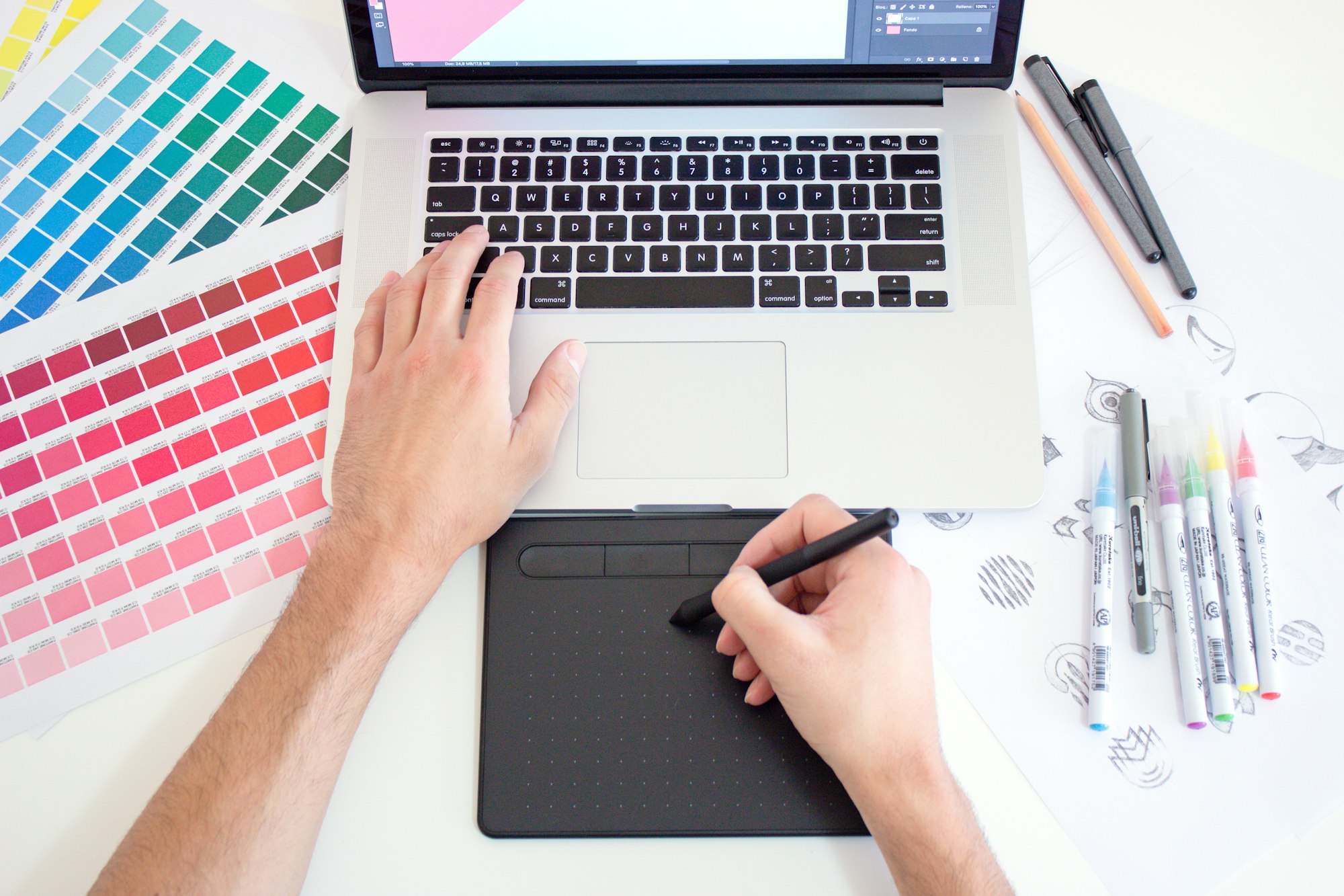 A designer working with a tablet, laptop and color charts