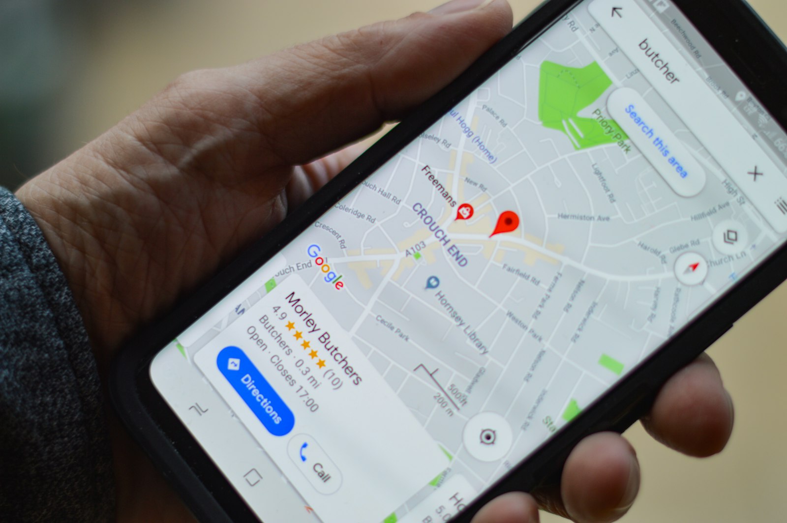 A hand holding a phone showing a business listing on a map