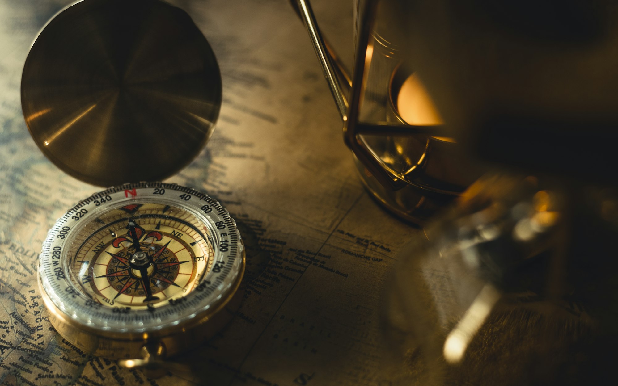 An antique compass resting on a dark desk