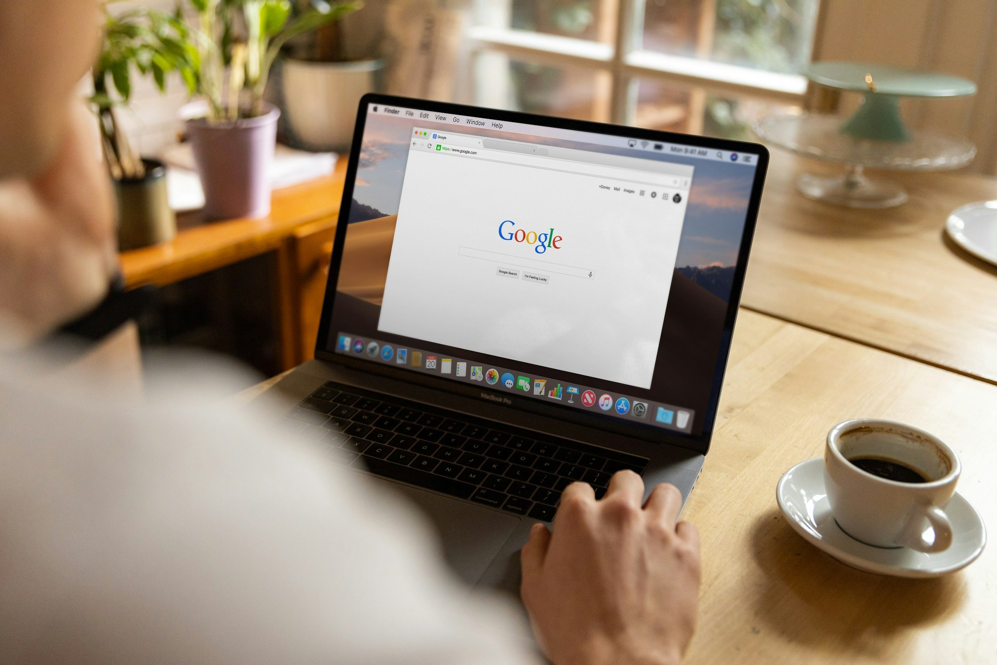 Someone searching on a laptop with a coffee beside it