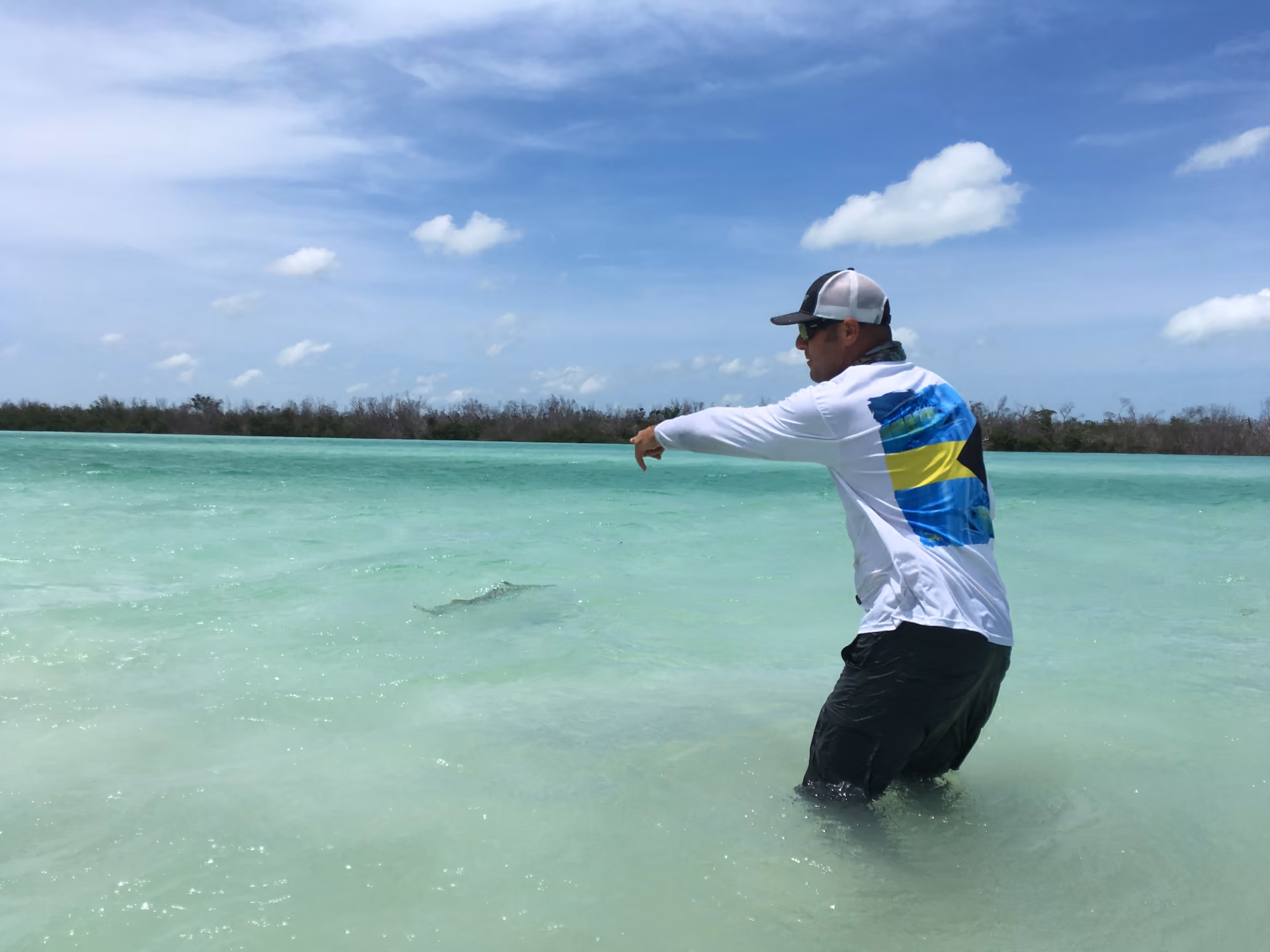 An angler wading a turquoise flat in the Florida Keys, casting toward the mangroves